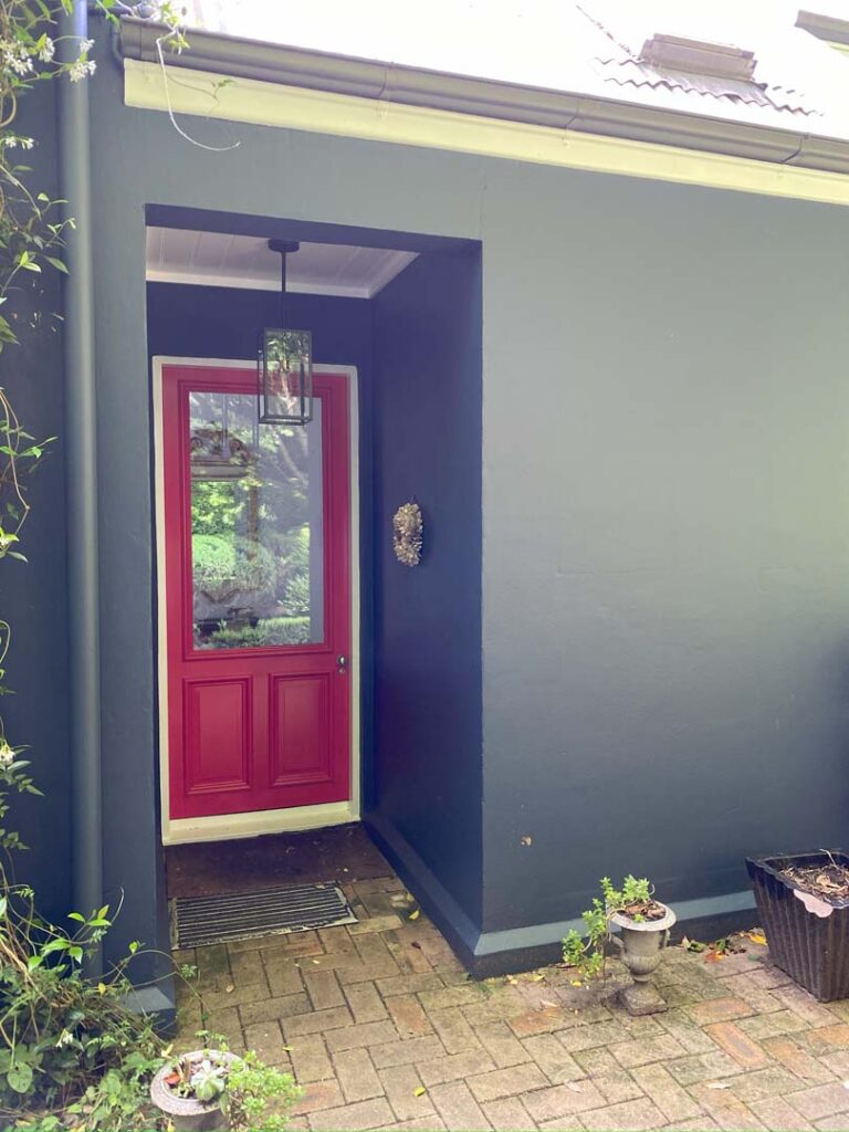 A charcoal painted wall with a red accent colour door
