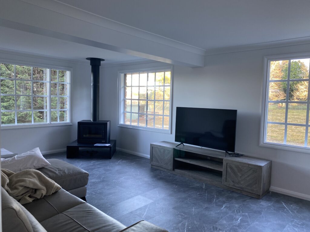 A freshly painted living room with white walls, large windows, and a modern design. A great example of how much paint is needed for an interior painting project.