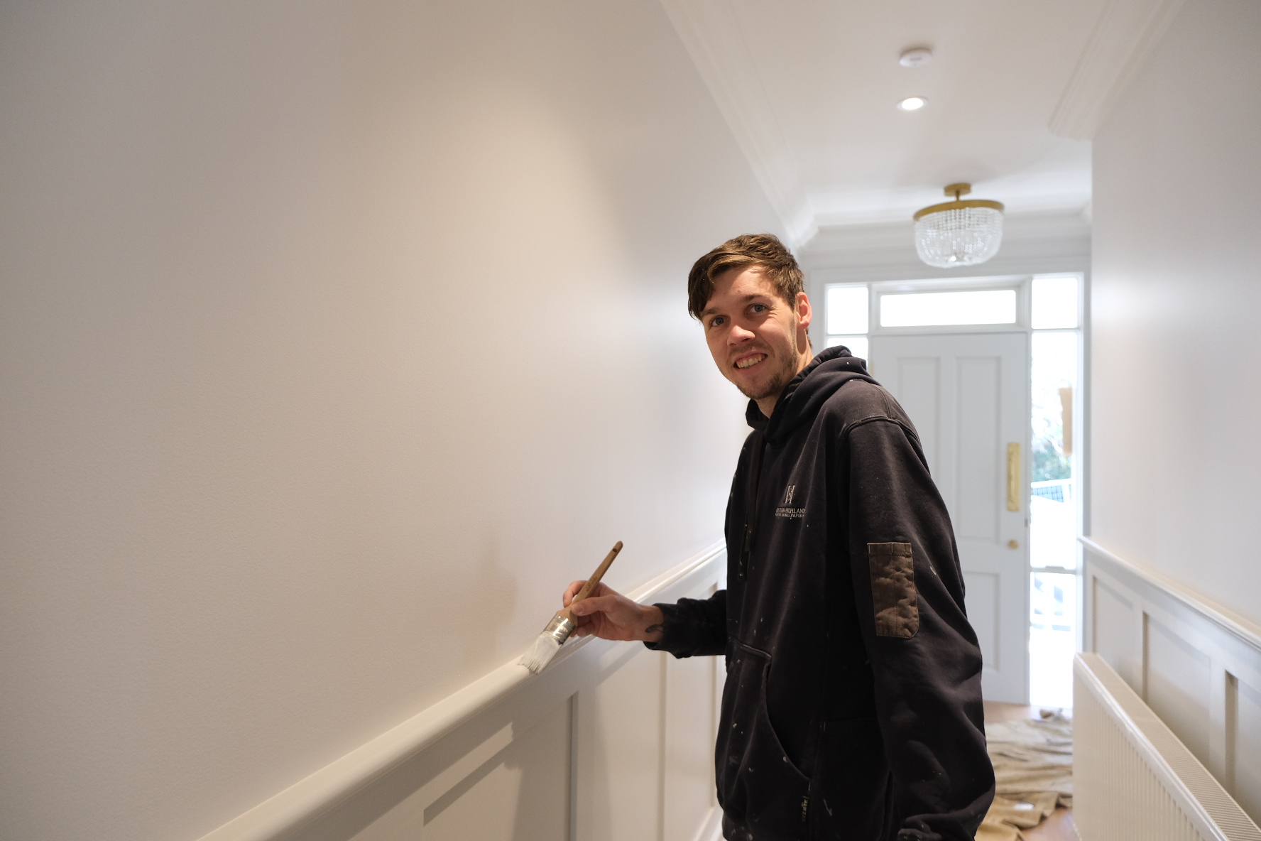 Joel from SHPW painting a narrow hallway white to create a vibrant entry way to home