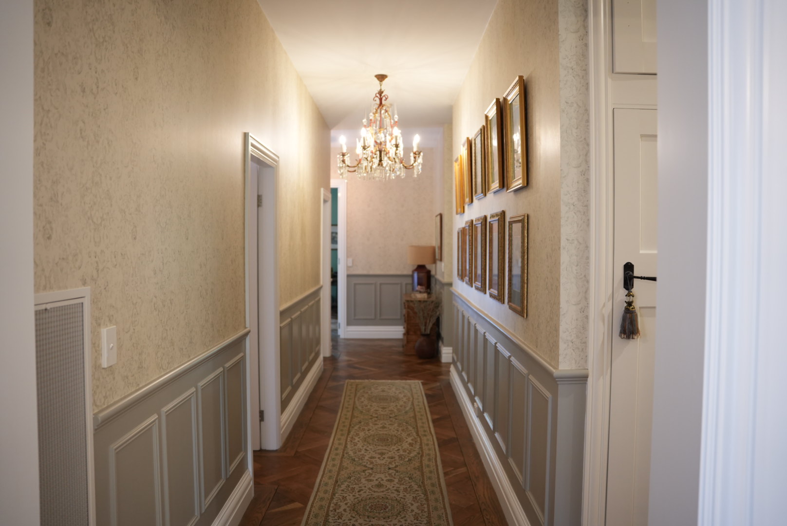 A home hallway with blue/grey accent panels contrasted with a wooden floor boards and cream walls.