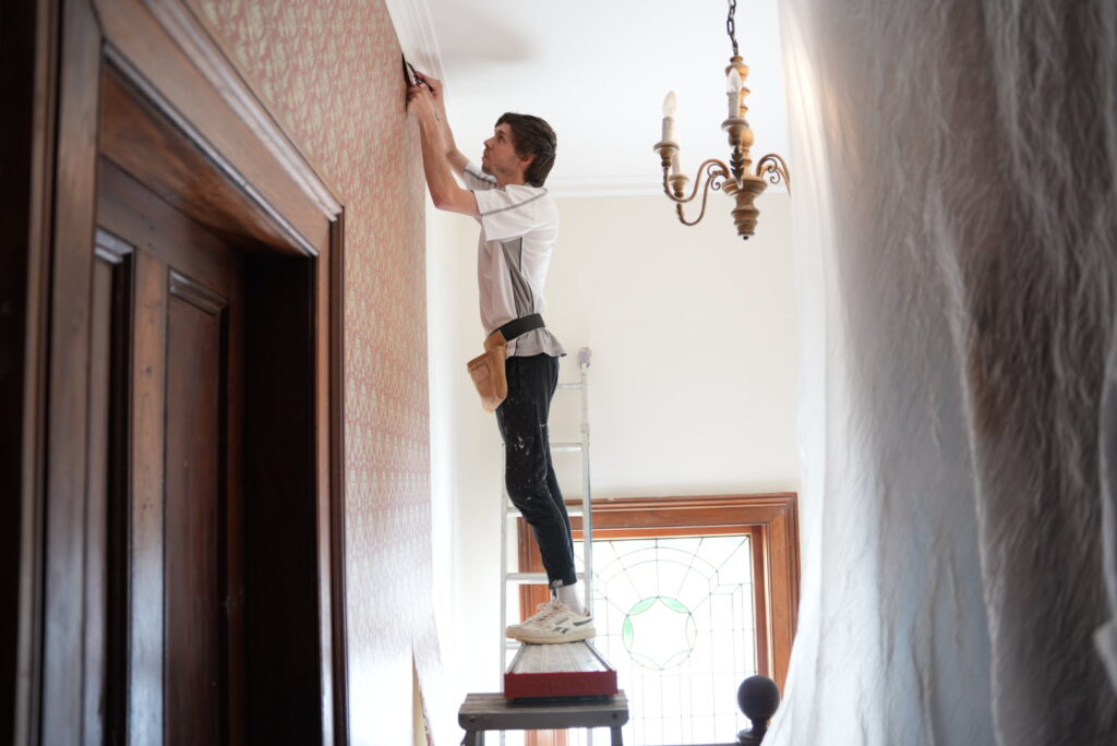 Joel from Southern Highlands Painting and Wallpapering installing red textured wallpaper at home in Mittagong